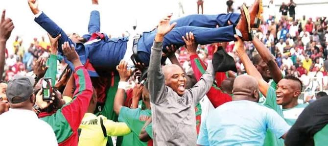 Celebration: Players lift a teammate in front of a packed stand.